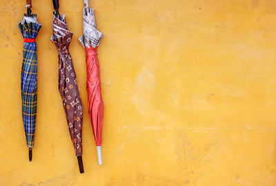 Close-up of multi colored clothes hanging on yellow wall