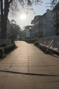 Footpath by buildings in city against sky