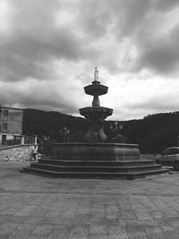 Statue in city against cloudy sky