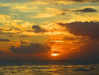 Scenic view of sea against dramatic sky during sunset