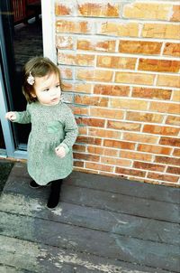 Boy standing against brick wall