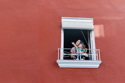 Portrait of woman in window against wall