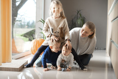 A mother with her three children playing on the floor at home