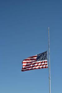 Low angle view of american flag against clear blue sky