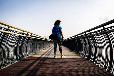 Rear view of woman standing on footbridge