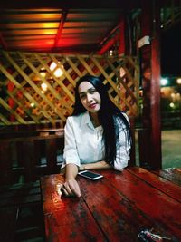 Portrait of young woman sitting at table in restaurant