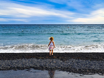 Full length of child walking at beach against sky on the mediterranean sea