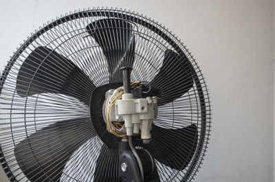 Close-up of electric fan against wall