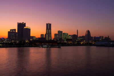 Illuminated buildings in city against sky during sunset