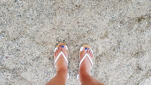 Low section of woman standing on sand at beach