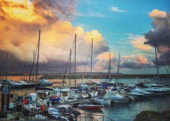 Boats moored in harbor at sunset