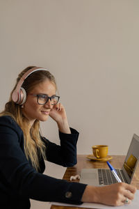 Woman working at home with laptop and papers on desk and headphones. home office . gray notebook 