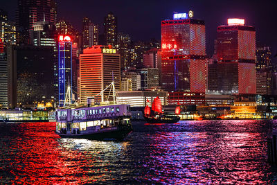 Illuminated modern buildings by river at night