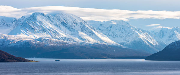 Scenic view of snowcapped mountains by sea against sky