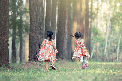 Rear view of twin sisters running in forest