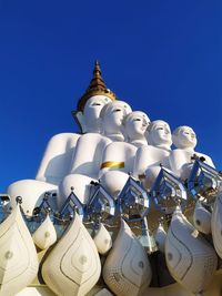 Low angle view of statue against building against clear blue sky