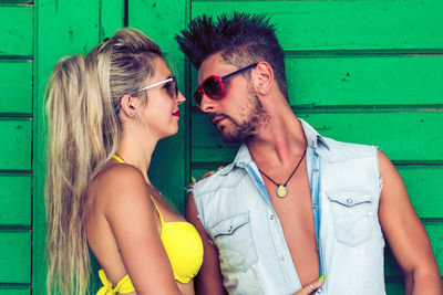 Couple wearing sunglasses against green wall