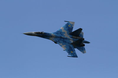 Low angle view of airplane flying against clear blue sky