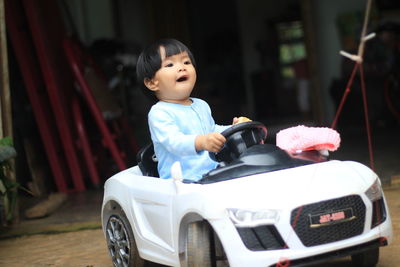 Cute girl eating food while sitting in toy car