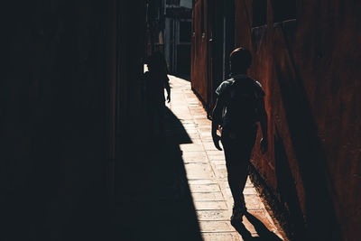 Rear view of man walking on footpath