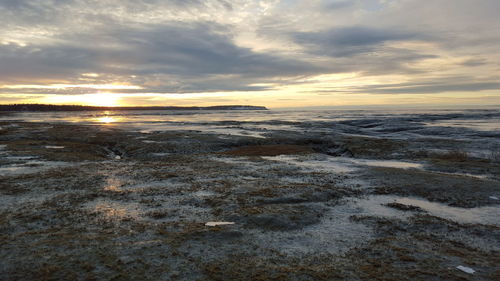 Scenic view of beach against sky during winter at sunset