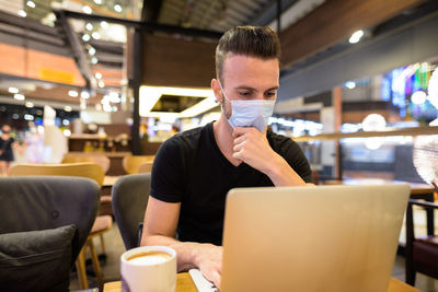 Man working on laptop sitting at cafe