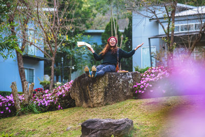 Smiling woman sitting on rock at park