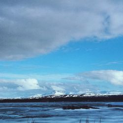 Snow covered landscape against cloudy sky