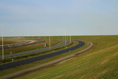 Road amidst field against sky