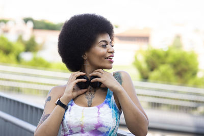 Portrait of smiling woman standing on railing in city