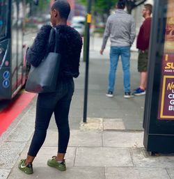 Rear view of woman walking on sidewalk in city