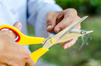 Midsection of man cutting cigarette with scissors
