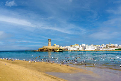 Scenic view of sea by buildings against sky