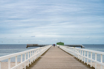 Rear view of pier over sea against sky