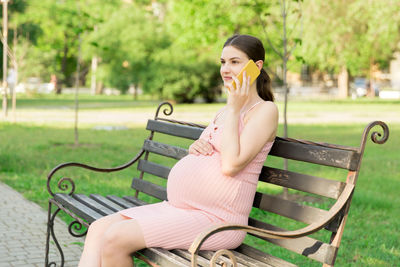 Young woman sitting on bench in park