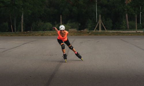 Full length of woman inline skating on street against trees