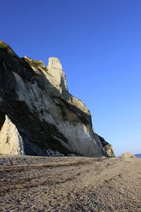 Low angle view of rocks against clear blue sky