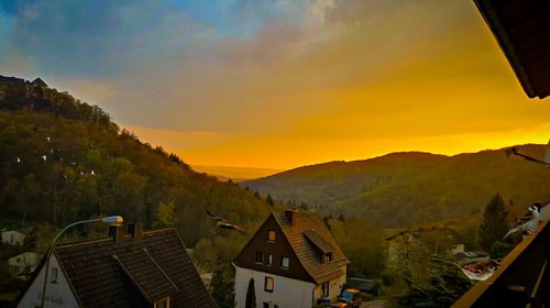 Aerial view of townscape and mountains against sky at sunset