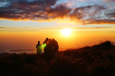 Silhouette people looking at sunset