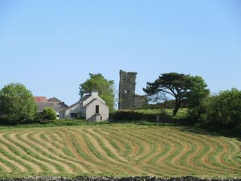 Houses on field against clear blue sky