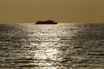 Silhouette boat sailing in sea against sky during sunset