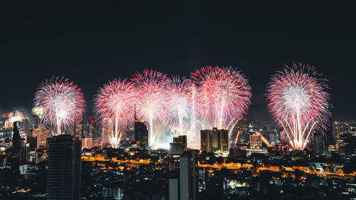 Firework display over illuminated buildings in city at night