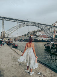 Woman standing on bridge against sky