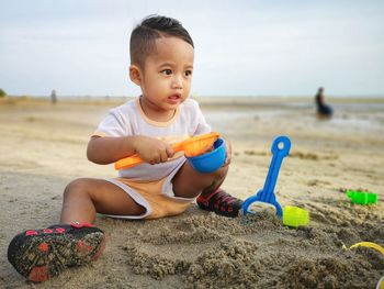 Cute boy playing with sand at beach