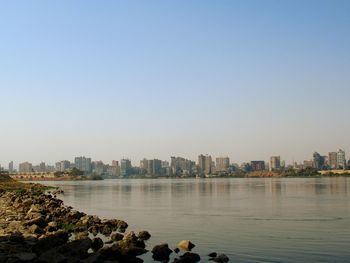 Scenic view of river by buildings against clear sky