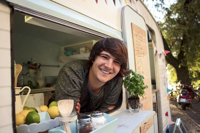 Portrait of happy male owner leaning on food truck window