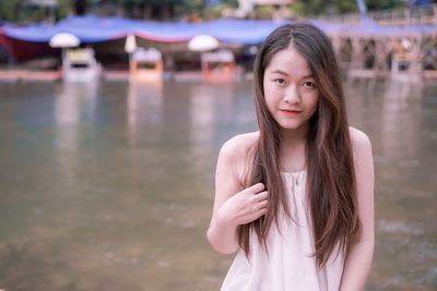 Portrait of beautiful young woman standing against lake