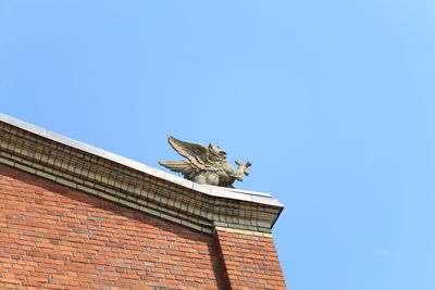 Low angle view of horse statue against clear blue sky