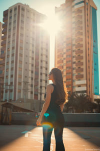 Full length of woman standing against sun in city