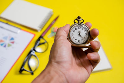 Close-up of human hand holding clock